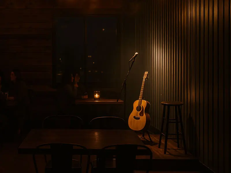 Candle-lit tables and guests enjoying live acoustic music at Wilson’s Grill in Hilliard, Ohio, with a guitar on stage under warm Edison bulbs