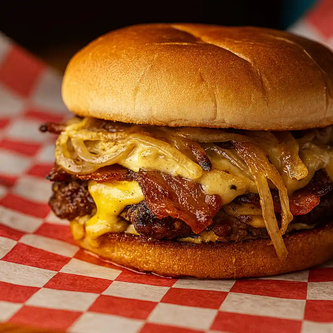 Broadside Smash burger with applewood bacon, sautéed onions, melted American cheese, and house plunder sauce on a smash burger patty at Wilson’s Bar & Grill in Hilliard Ohio