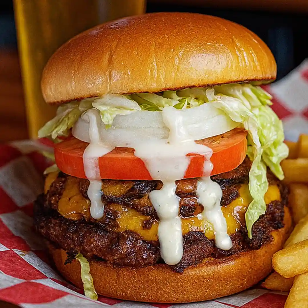Wilson Smash burger with American cheese, sautéed mushrooms cooked in ErryTang hot sauce, tomato, onion, lettuce, and house No. 07 sauce at Wilson’s Bar & Grill in Hilliard Ohio